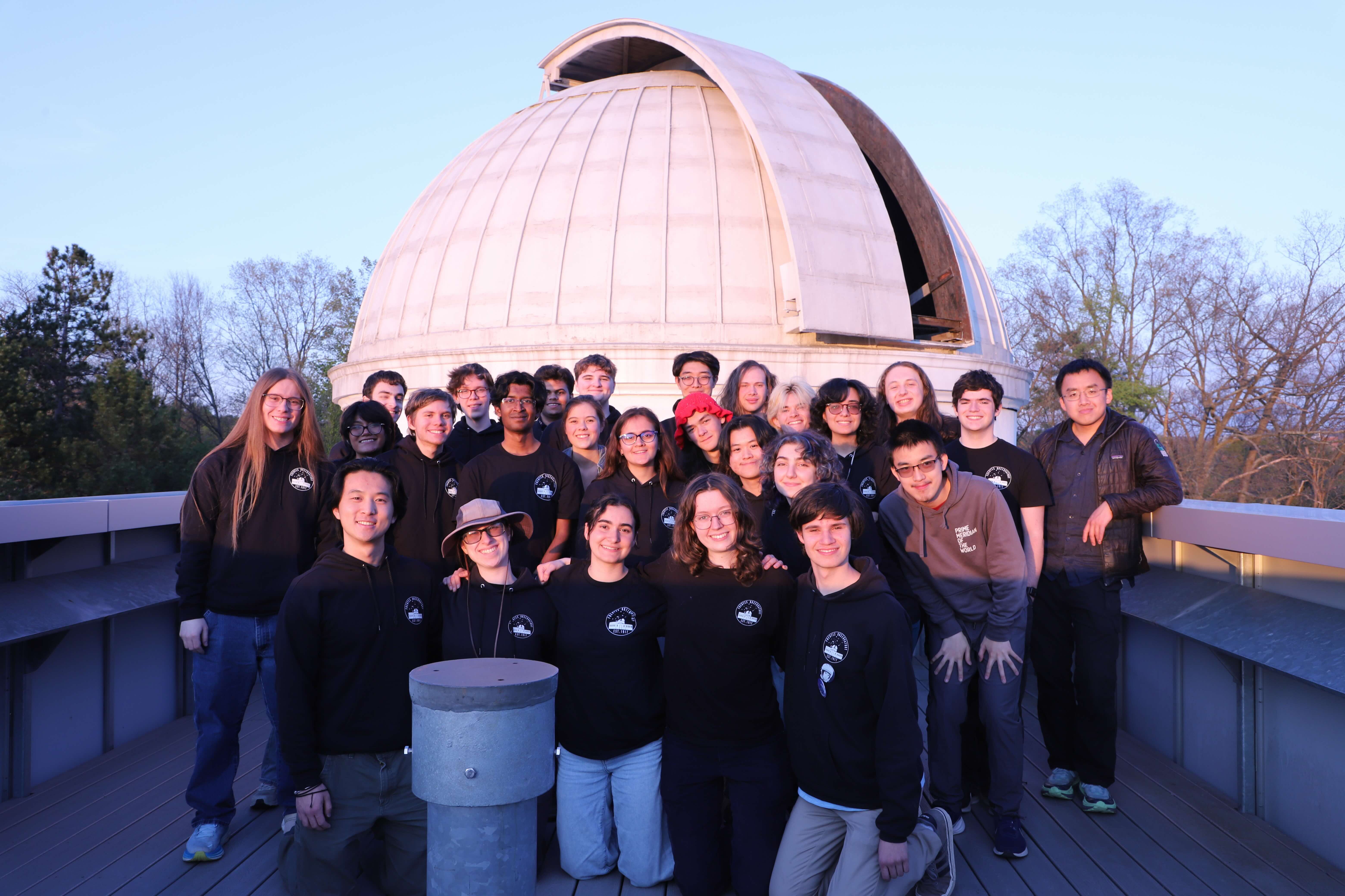 Members of the Cornell Astronomical Society posing for a photo inside the dome of the Fuertes Observatory, with the Irving Porter Church Memorial Telescope visible in the center.